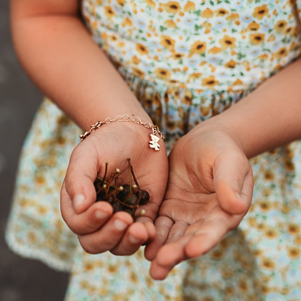 Teddy Bear Charm in Rose gold on charm bracelet worn by young tween in a floral dress